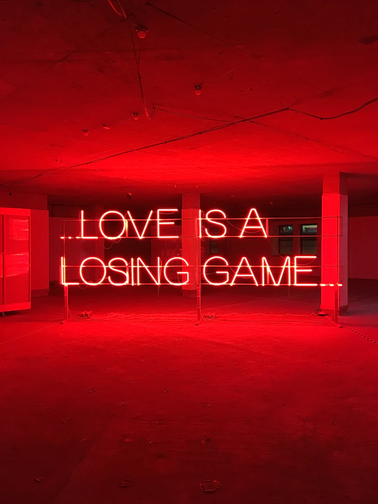 Neon sign that says love is a losing game