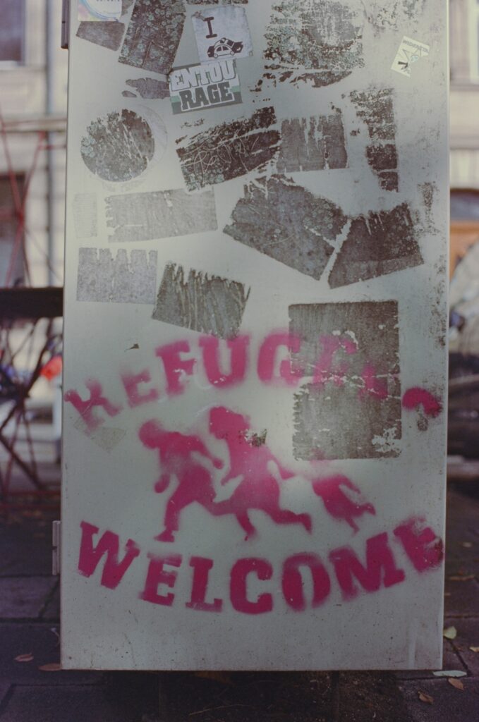 Image of spray painted sign saying refugees welcome