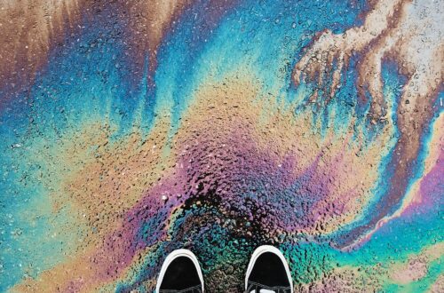 Someone's view of their sneakers standing on rainbow pavement