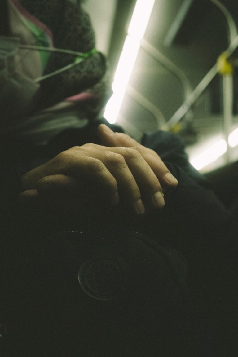 hands clasped together on someone's lap in a subway