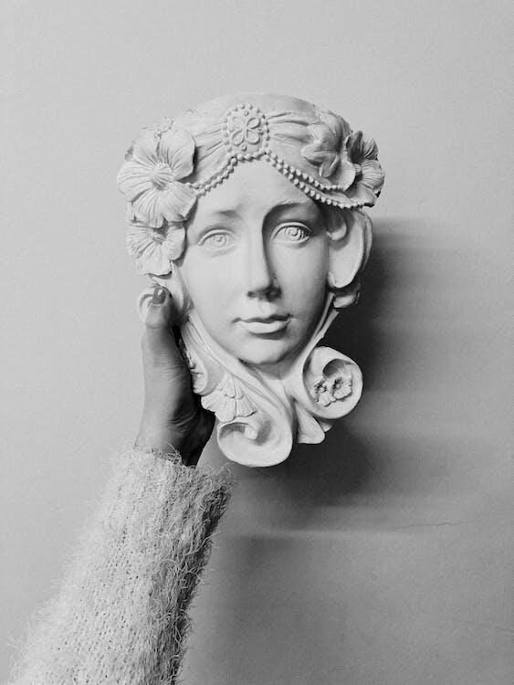 a sculpture of a woman's face being held by someone's hand